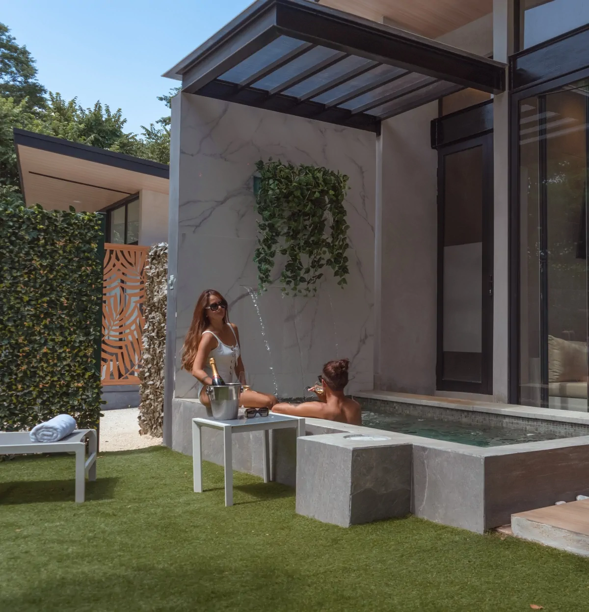 Woman relaxing by infinity pool on modern villa terrace with marble wall and contemporary outdoor furniture at luxury Costa Rica resort